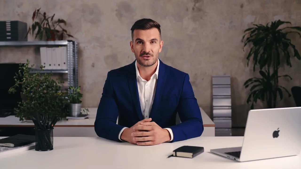 Person zeigt auf eine Präsentation an einem Bildschirm, davor mehrere Zuhörer